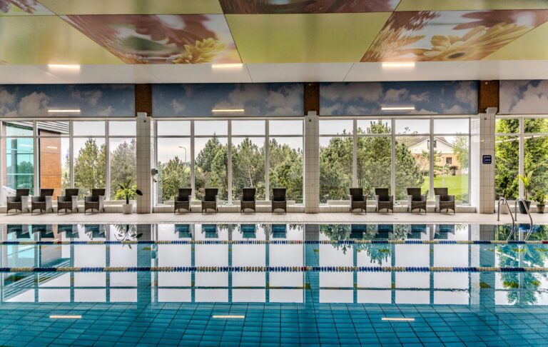 Toila Spa swimming pool: the pool, a row of loungers and large windows onto the park, symmetrical view