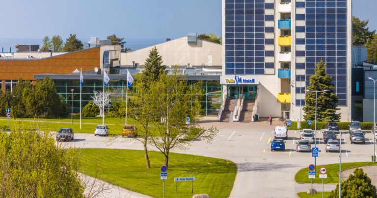 Главный вход отеля Toila Spa, флаги и парковка, слева низкое здание спа, панорама с дрона