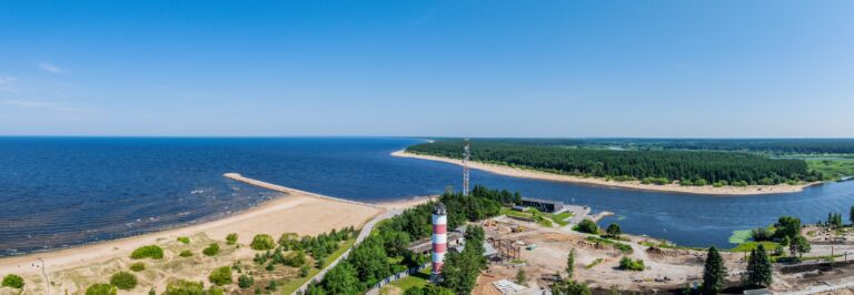 Wide drone panorama of the mouth of the Narva river: the beach, the breakwater, the lighthouse, the river and the forested far bank