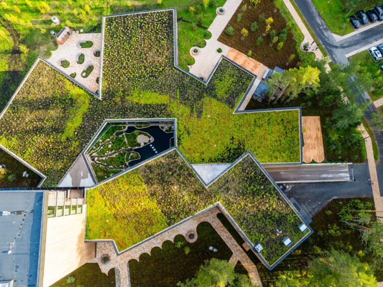 The star-shaped green roof of Kurro Spa from directly above with a garden courtyard in the middle, drone view