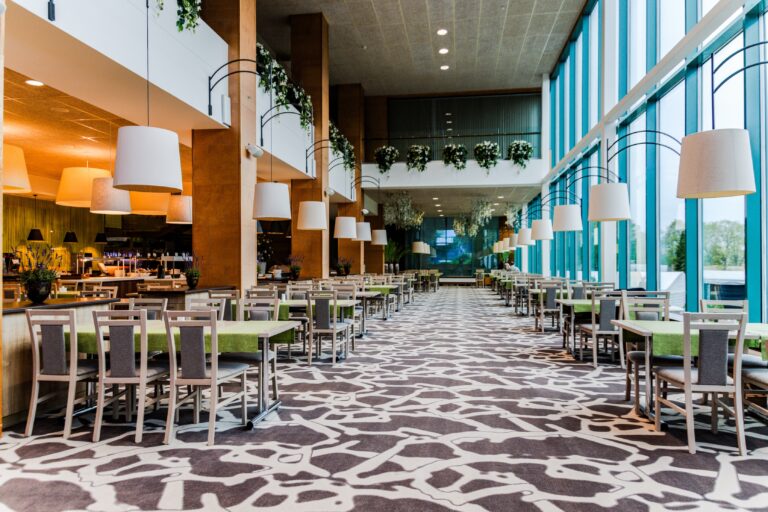 The double-height restaurant hall at Toila Spa: a glass wall, pendant lamps and rows of tables