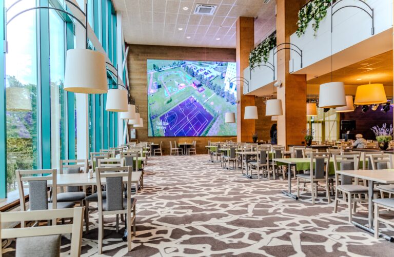 Toila Spa restaurant hall with a large screen wall, a glass wall and rows of tables