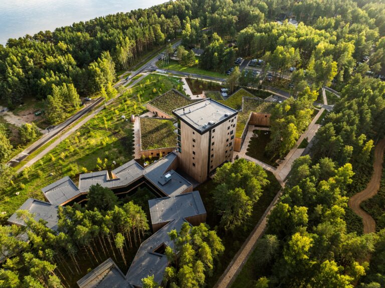 The Kurro Spa tower and low wings in the middle of the pine forest in evening light, drone view from above