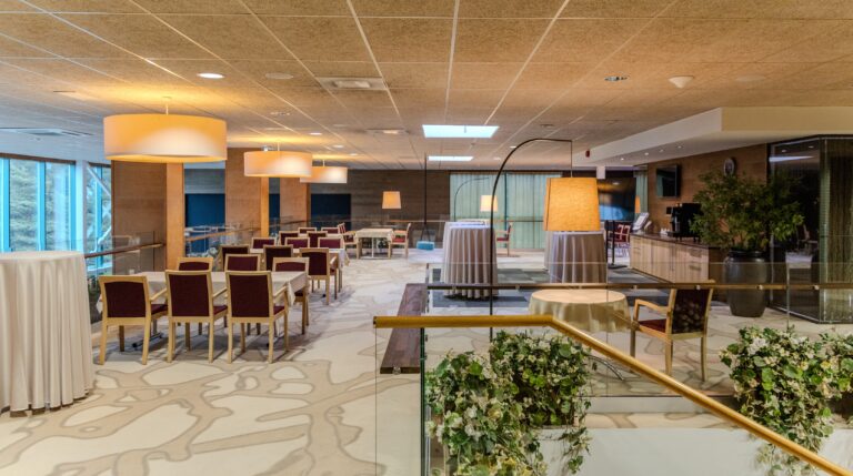 Upper level of the Toila Spa restaurant: tables, standing tables and a glass balustrade overlooking the hall below