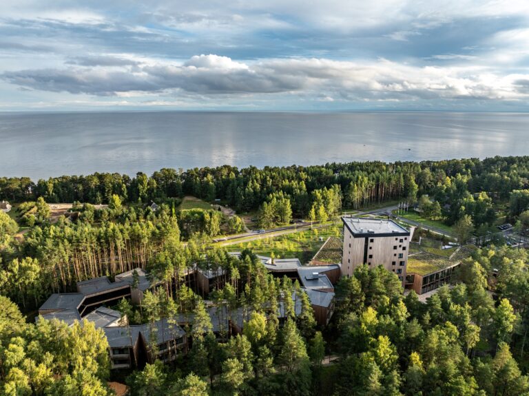 Kurro Spa in the pine forest with Lake Peipus and a cloudy sky behind, drone view
