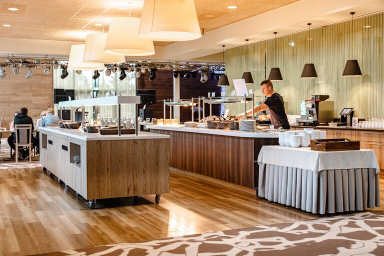 Buffet counters in the Toila Spa restaurant with a member of staff behind them and pendant lamps above