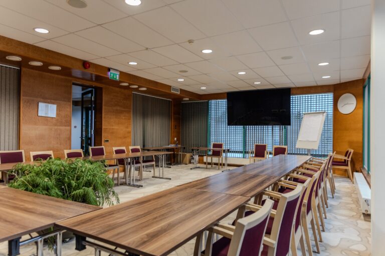 A seminar room at Toila Spa: long tables, chairs, a screen and a flip chart