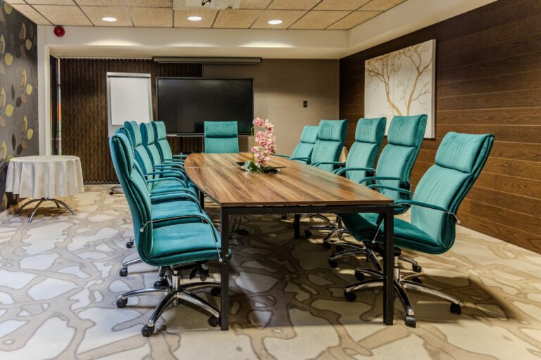 A meeting room at Toila Spa: a long timber table, turquoise chairs and a screen