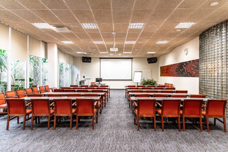 Toila Spa conference hall: orange chairs in rows behind tables, a screen and a glass-block wall