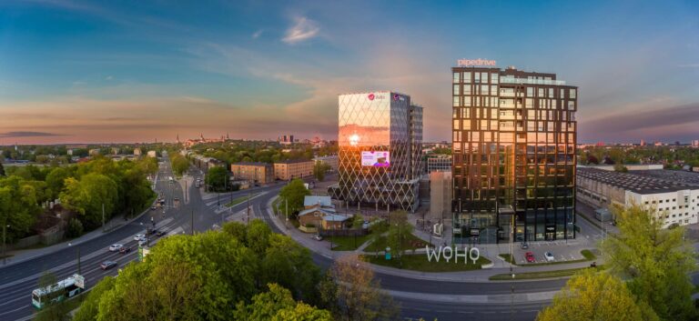 Woho büroohooned Pipedrive'i ja Telia siltidega õhtuvalguses, kõrval tänav bussi ja autodega, droonipanoraam