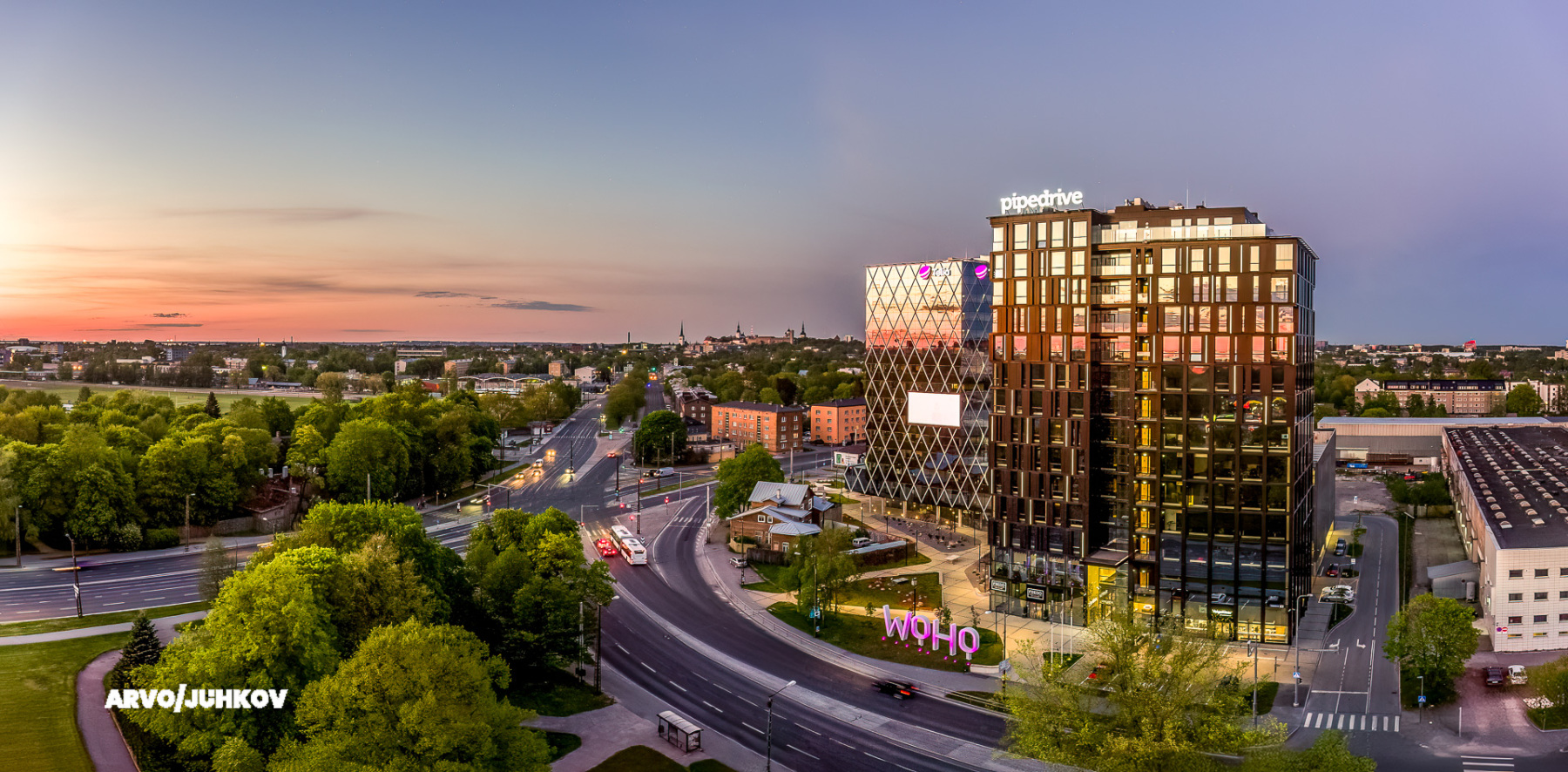 Woho büroohooned oranži loojangutaeva taustal, all ristmik ja puud, droonipanoraam