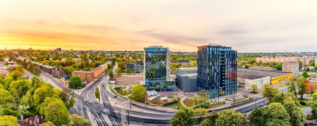 Woho kaks büroohoonet Tallinnas kevadise loojangutaeva all, ümber rohelus ja ristmik, droonipanoraam
